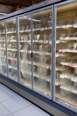 A person walks past empty refrigerators at an Intermarché supermarket in Névez, France, on Monday.