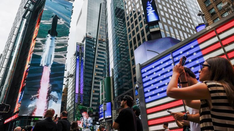 People gather near a SpaceX advert, on the day of SpaceX's initial public offering (IPO) at the Nasdaq MarketSite, in New York City, on June 12, 2026.