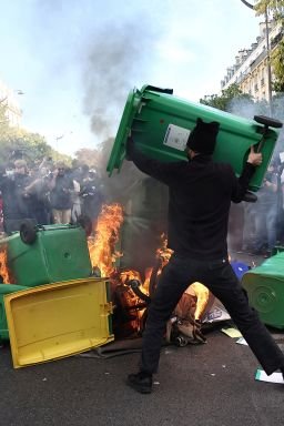 A protester throws a garbage bin into burning objects during a demonstration by high school and university students, in Paris on Tuesday, as part of a nationwide day of protests over overcrowded classrooms, teacher shortages and dilapidated school buildings.