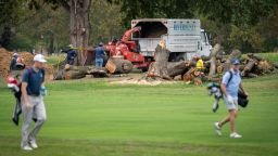 Golfers pass workers as trees are cut down at East Potomac Golf Links, Saturday, October 10, 2026, in Washington. (AP Photo/Nathan Howard)