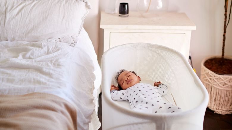 Three month old baby asleep in his cot beside the bed in his motherâ"u20acs bedroom