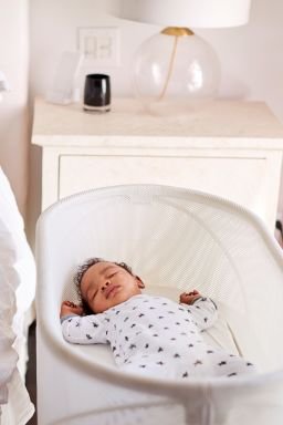 Three month old baby asleep in his cot beside the bed in his motherâ"u20acs bedroom