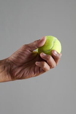 A hand holds a tennis ball.