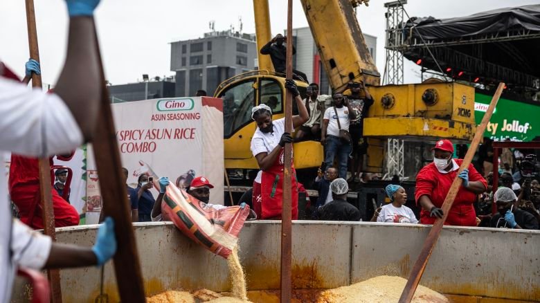 Nigerian chef Hilda Baci (C) stirs as staff members pour rice in a giant pot during an attempt to break the world record for the largest pot of Jollof rice, led by Baci in Lagos, on September 12, 2025.