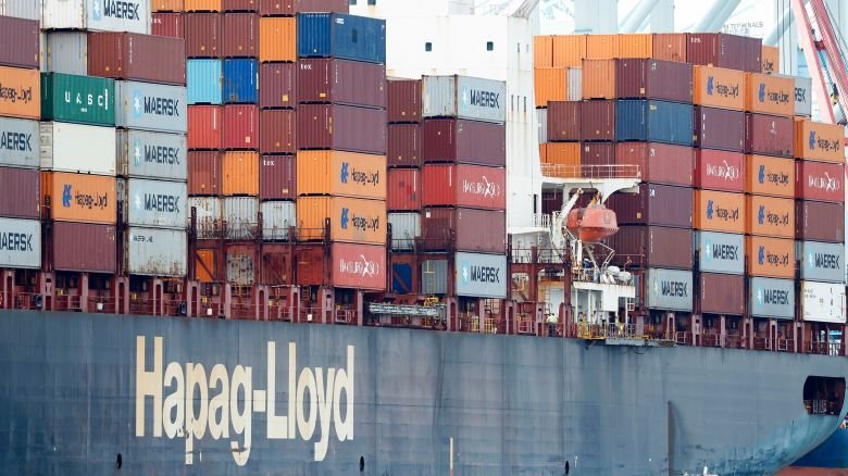 A vessel passes a container ship loaded with shipping containers at the Port of Los Angeles on February 20, 2026.