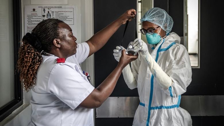 A nurse is assisted by a colleague in donning personal protective equipment (PPE) at an isolation facility prepared to receive potential Ebola patients during a media visit to Nairobi Hospital in Nairobi on October 7, 2026. Kenya has reported its first-ever Ebola death, the health minister announced on October 6, 2026, after a Kenyan man who had been living in the Democratic Republic of Congo died after returning to the country. (Photo by Luis TATO / AFP via Getty Images)