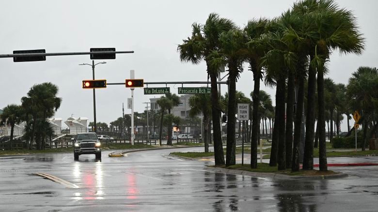 A car drives along a road in Pensacola Beach, Florida, on October 9, 2026, as Hurricane Isaias moves north toward the Florida Panhandle. Hurricane Isaias intensified to Category 2 in the Gulf of Mexico's warm waters on Thursday as it churned toward the southern United States, the National Hurricane Center (NHC) said. The first hurricane of the Atlantic season, Isaias is forecast to make landfall in Florida, Alabama or Mississippi overnight Friday to Saturday, according to the NHC.