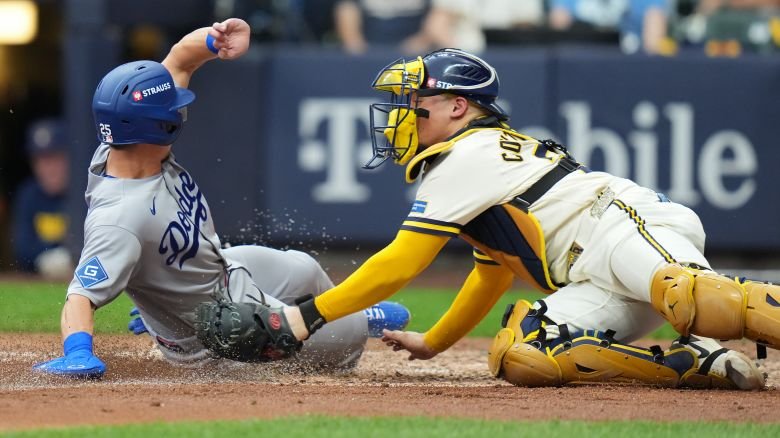 MILWAUKEE, WISCONSIN - OCTOBER 12: Tommy Edman #25 of the Los Angeles Dodgers slides into home plate to score a run past William Contreras #24 of the Milwaukee Brewers in the fifth inning in game two of the National League Championship Series at American Family Field on October 12, 2026 in Milwaukee, Wisconsin.  (Photo by John Fisher/Getty Images)