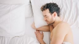 Overhead view of young man lying asleep in bed