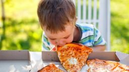 funny toddler eats pizza without using his hands
