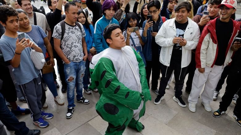 A young person dressed as a frog takes part in the first ''Aura Farming'' battle on the esplanade of the Palace of Fine Arts in Mexico City, Mexico, on August 20, 2026. Participants gather for an open-air performance involving an exchange of movements, dance, acrobatics, physical feats, and gestures, each adapted to the individual's personality.